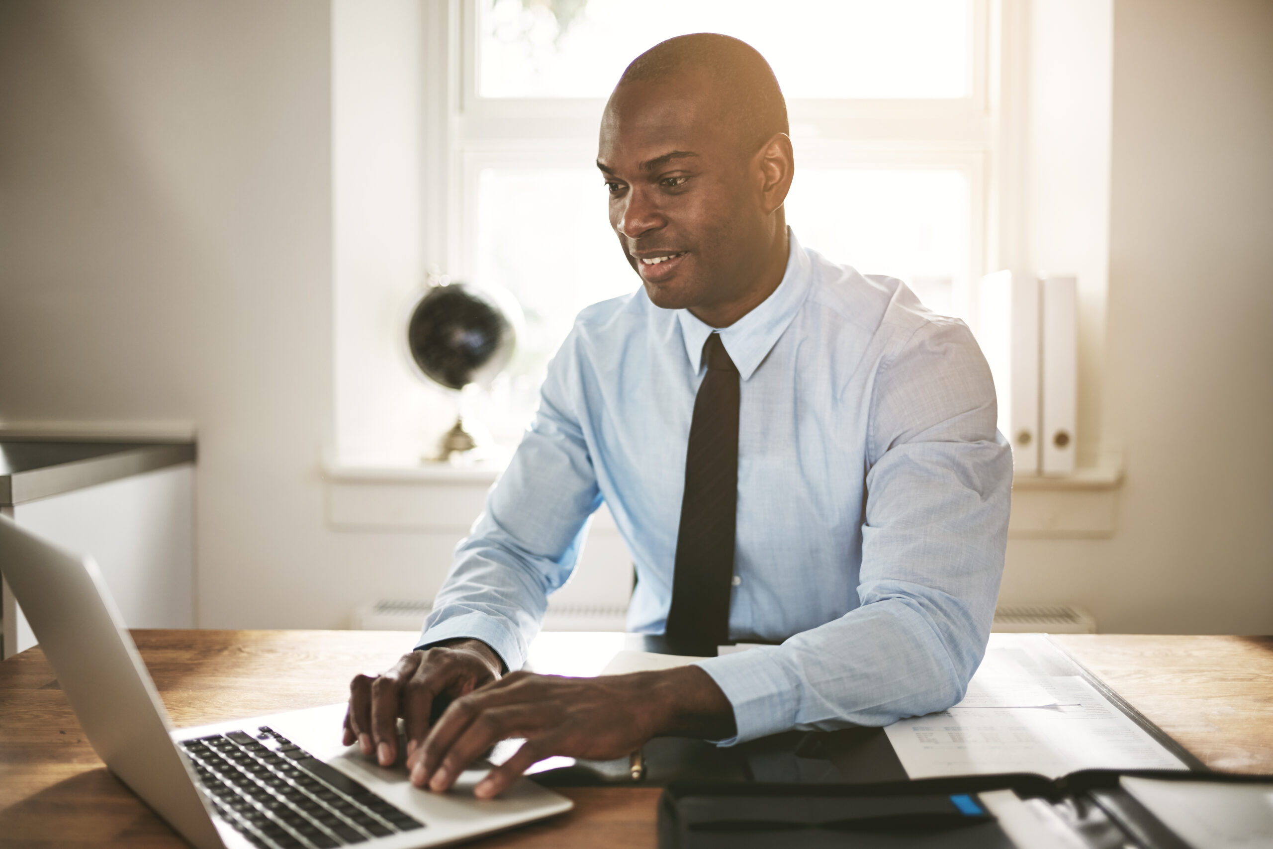 Smiling young executive sitting at his desk working online
