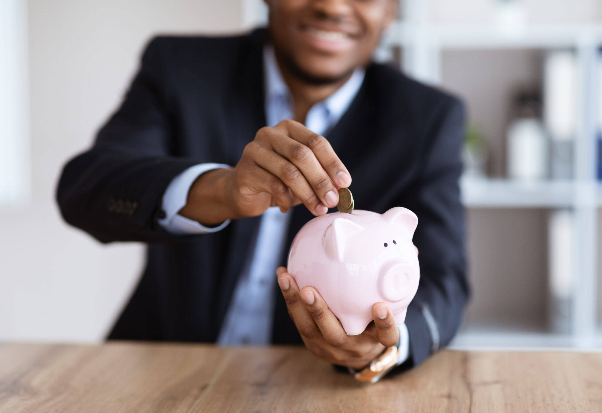 Cropped of black businessman putting money in piggy bank